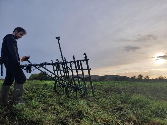 Dr Patrick Gleeson doing some some gradiometry surveying A man pushes a machine across a field to do some some gradiometry surveying