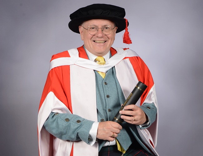 Professor Murray Pittock. Credit RGU A man sites on a chair in full honorary graduation cap and gown