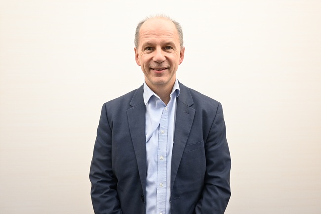 Professor Colin Berry. Copyright NHS Golden Jubilee. A man in a suit stands in front of a white background.