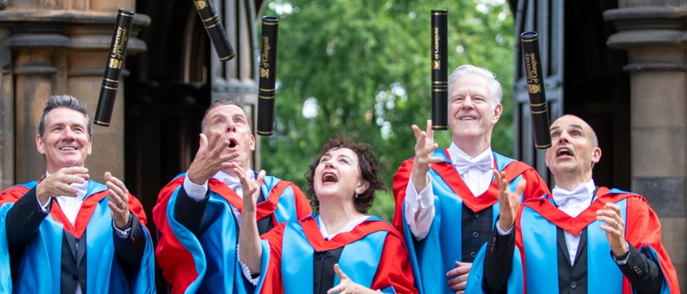 Members of the band Deacon Blue in graduation robes throwing honourary diplomas up in the air