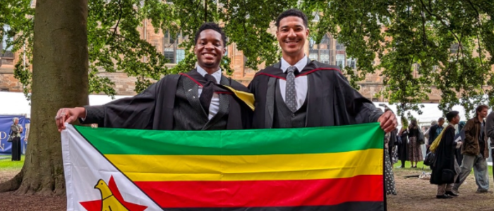 Ryan and Dylan standing in the east quad with the Zimbabwean flag on their graduation day