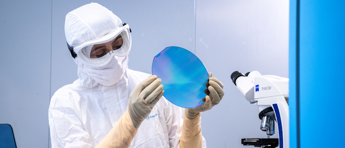 A lab technician in Chemistry works with electronics wearing protective clothing and goggles
