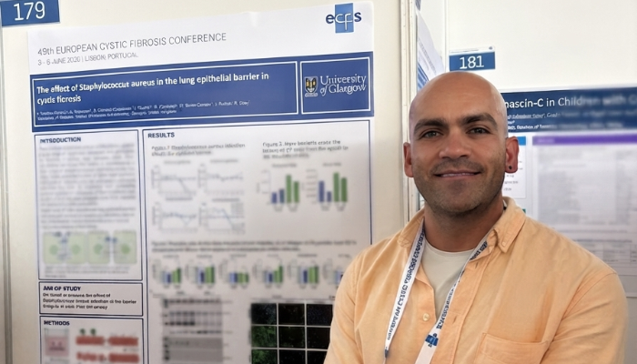 Dr Alfredo Montes Gomez stands beside his award-winning research poster at the 49th European Cystic Fibrosis Conference in Lisbon, Portugal. The poster, displayed at the University of Glasgow exhibition stand, presents research investigating the effect of Staphylococcus aureus on the lung epithelial barrier in cystic fibrosis.