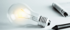 Lightbulb next to pen and paper