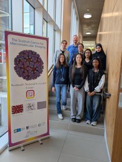 8 people posed on a staircase next to a large window. A pop-up banner promoting SCMI is in the foreground
