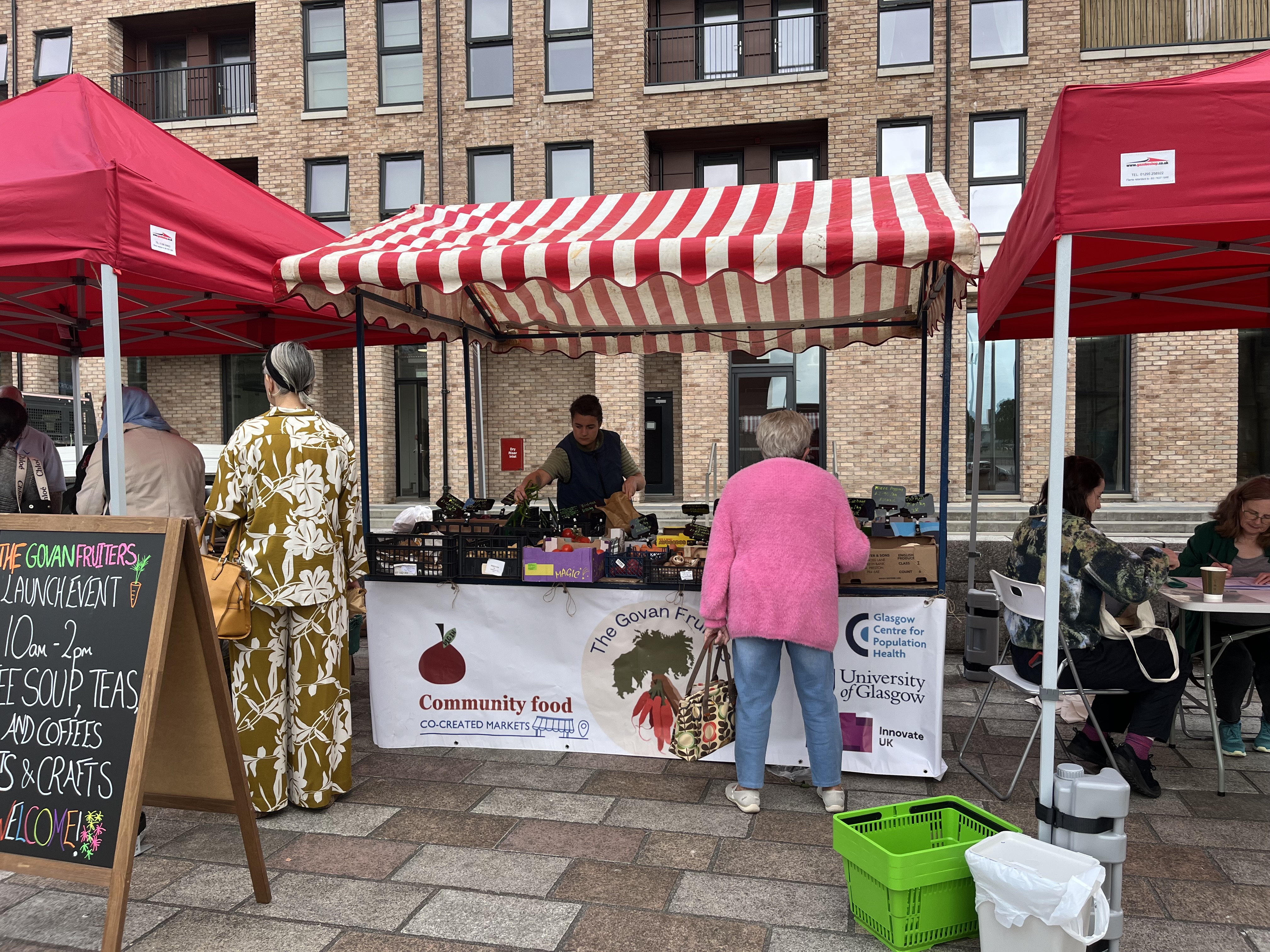 Market trader selling produce to customers in an outdoor market stall