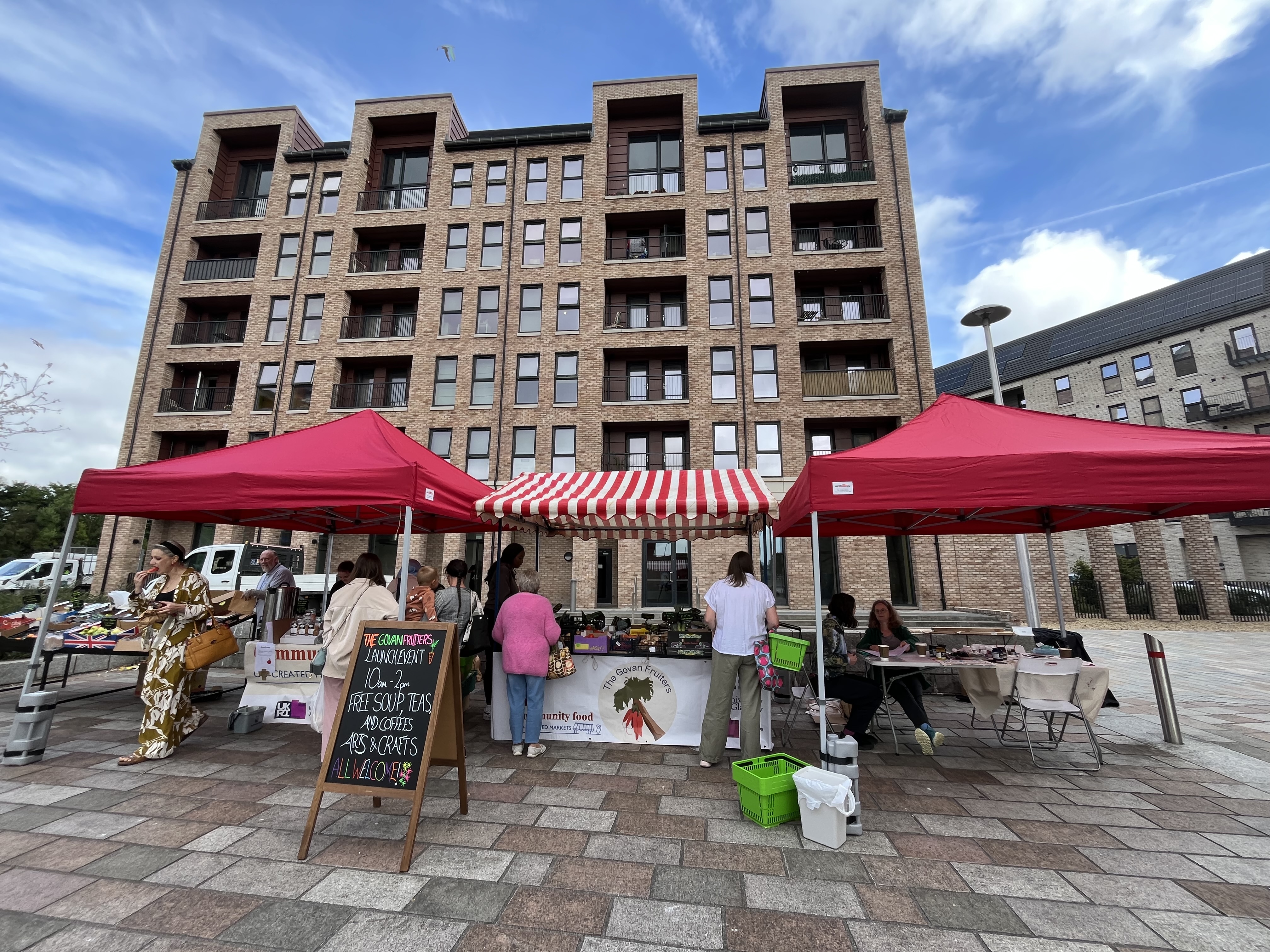 Wide horizontal shot of the govan fruiters market with customers buying produce