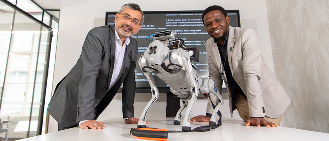 Professor Muhammad Imran and Dr Olaoluwa Popoola lean on either side of RoboGuide, a robotic guide dog prototype.