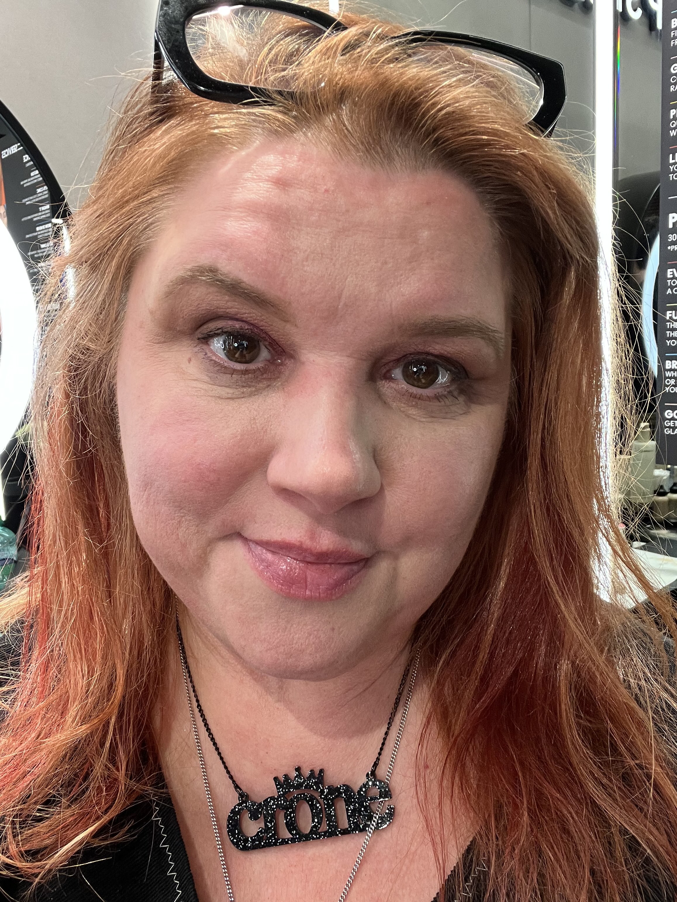 A woman with copper hair wearing a necklace that says Crone