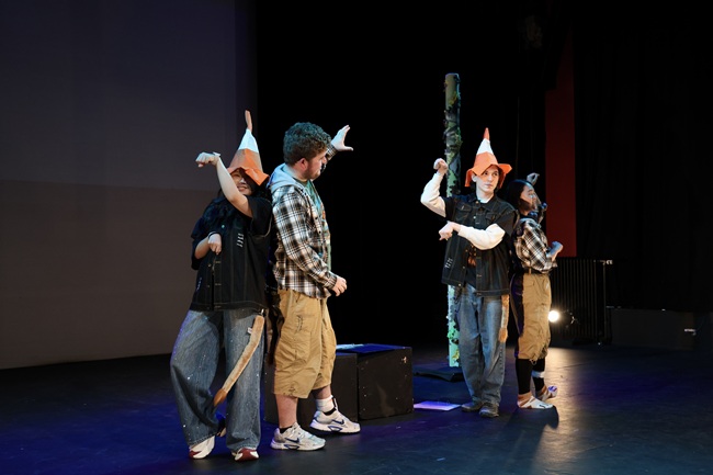 Left to right: Yijia Yuan; Shane Kenny, Dylan Traynor and Hsiao-chiang Wang. Credit Abigail Morris The cast of a play Lion and Unicorn stand on stage two wear traffic cone hats as unicorns and two wear lion t-shirts