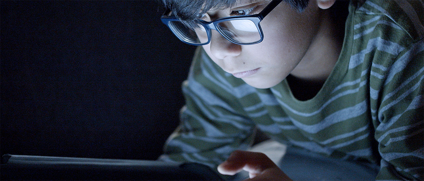 Young boy with glasses looking at mobile screen