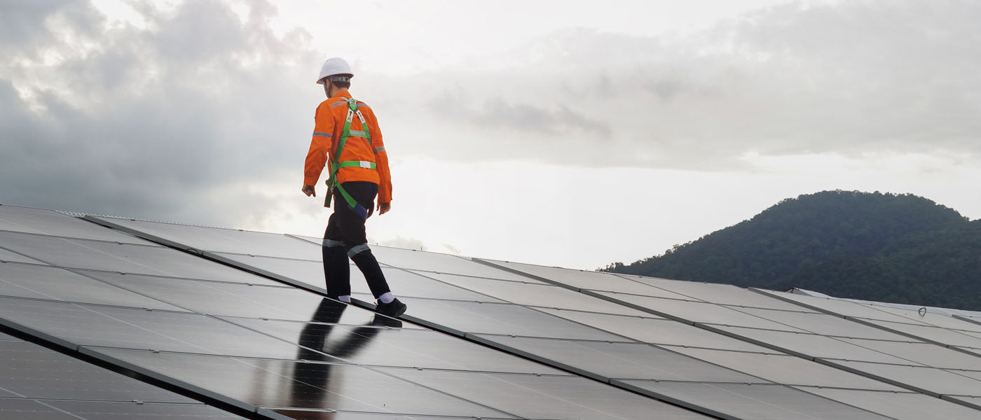 A technician installs a large photovoltaic system on an industrial rooftop.