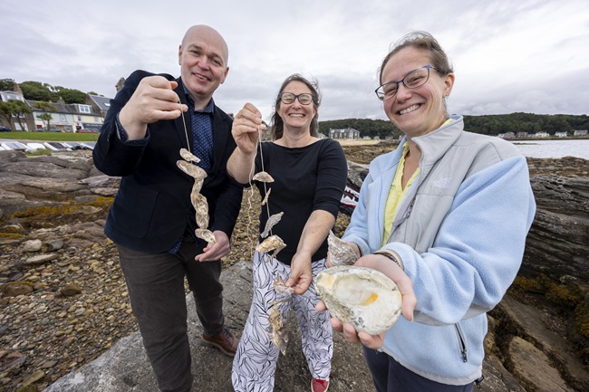 From left to right, Gillebrìde MacMillan, Dr Claire Ramjan and Dr Anna McGregor celebrate Project Eisirean in Millport where the new mobile oyster hatchery is based.