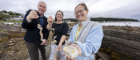 From left to right, Gillebrìde MacMillan, Dr Claire Ramjan and Dr Anna McGregor celebrate Project Eisirean in Millport where the new mobile oyster hatchery is based.