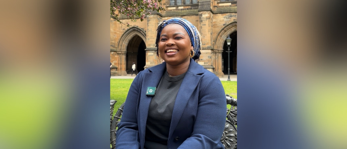 Dr Sofiat Olaosebikan sitting on a bench, posing for a photo in the west quad at uofg