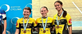 Three people wearing yellow cycling jerseys and medals smile for a photo after completing a cycling event.