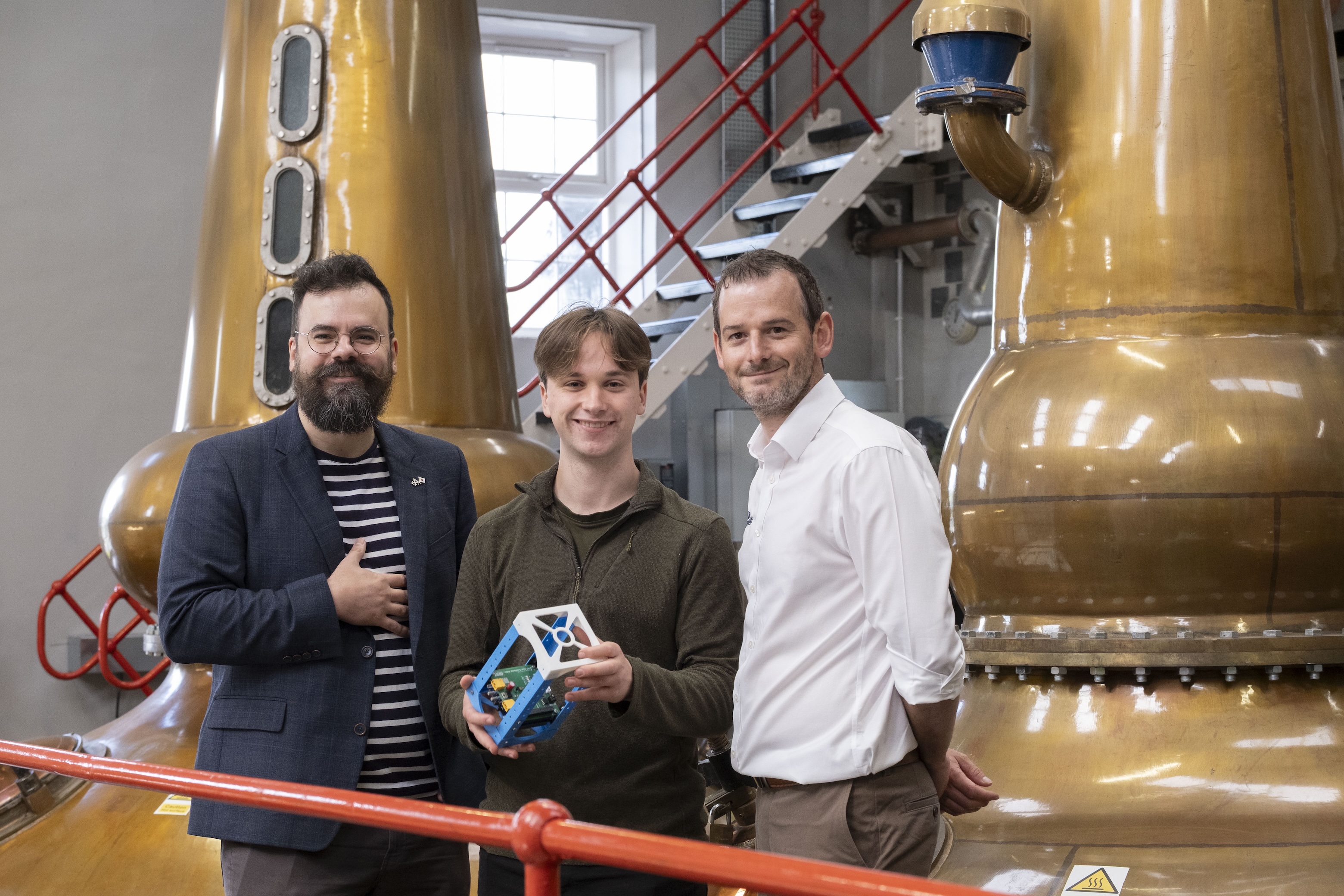Dr Gilles Bailet of the University of Glasgow’s James Watt School of Engineering, University of Glasgow engineering student Micah Chapman and Geoff Nisbet of Allen Associates examine prototype space equipment at Glengoyne Distillery, Dumgoyne