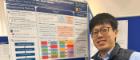 Dr Takayuki Ando, a smiling Japanese doctor standing next to an academic poster