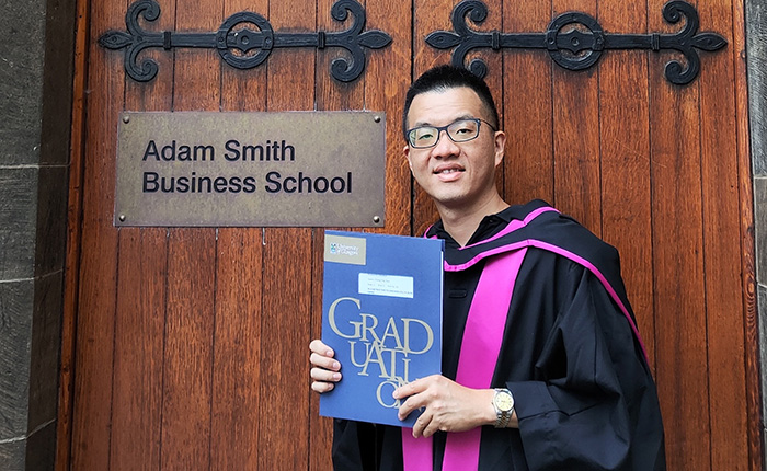 Cheng-ting (Steven) Tsou holding a certification from the Adam Smith Business School during graduation
