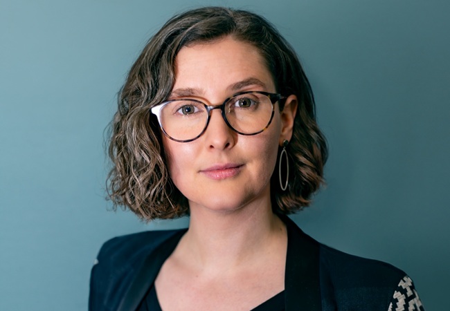 A portrait of a woman wearing glasses looking into the camera lense.