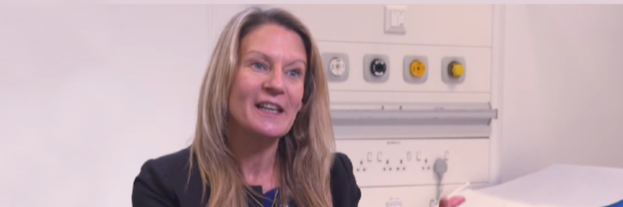 Dr Eve Smith, Sii Paediatric Rheumatologist, speaking and gesturing during an interview with STV News in a hospital setting.