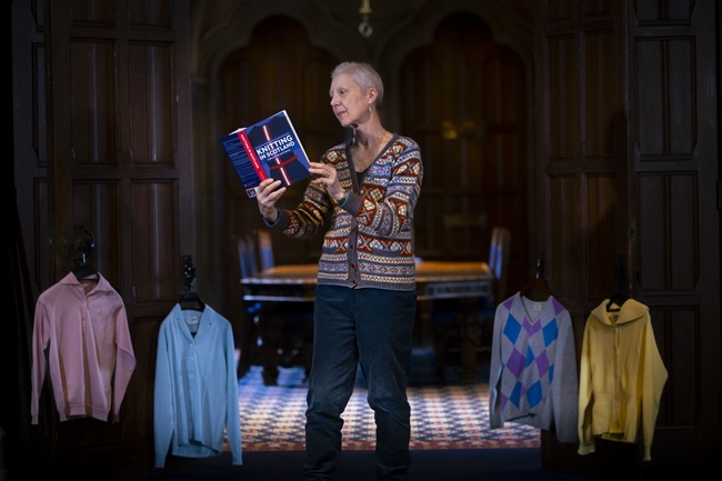 Professor Lynn Abrams with a selection of Scottish knitwear. Credit Martin Shields A woman stands in the doorway of a corridor reading a book - Knitting in Scotland - surrounded by examples of Scottish knitwear. Credit Martin Shields
