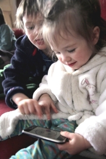Image of two children playing with iPhone and game