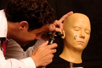 Medical student learning clinical skills by looking into the ear of a model of a head with an auriscope © Corporate Communications University of Glasgow