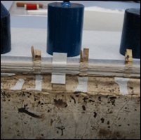 This photograph shows the textblock being attached to the cover of the logbook with parchment sewing support strips during conservation treatment.  (GUAS Ref: UGC 182. Copyright reserved.) 