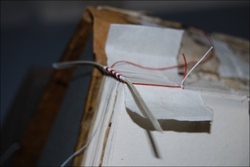This photograph shows the method of sewing two colour headband with one thread over a parchment strip during conservation treatment.  (GUAS Ref: UGC 182. Copyright reserved.) 