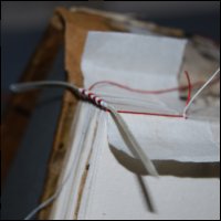 This photograph shows the method of sewing two colour headband with one thread over a parchment strip during conservation treatment.  (GUAS Ref: UGC 182. Copyright reserved.) 