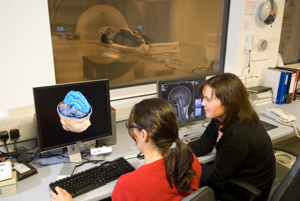 Two staff members sitting at computer screens looking at MRI scan