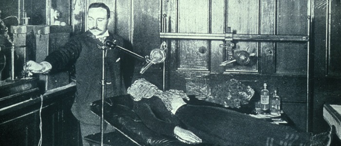 Dr Macintyre in his lab  taking an X-ray of woman on couch, courtesy of Medical Illustration Services, Glasgow Royal Infirmary