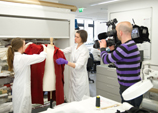 Conservators in the textile conservation lab being filmed by a news crew