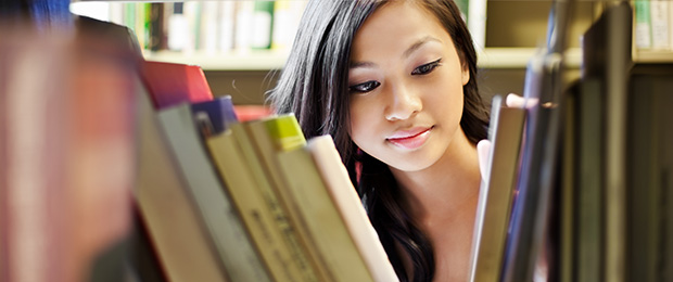 female student looking through books in a library