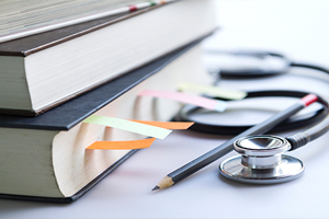 Medical student textbooks with pencil and multicolor bookmarks and stethoscope