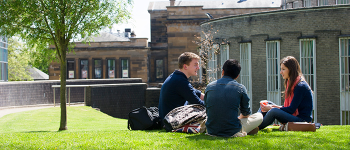 three students sitting on grass outside Glasgow University Reading Room