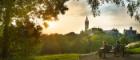 Main building and tower from park at sunset, students on bench in foreground