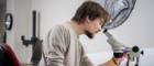 A classics researchers working in a lab with a microscope