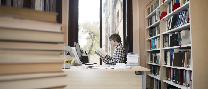 a staff member working at University Gardens surrounded by books