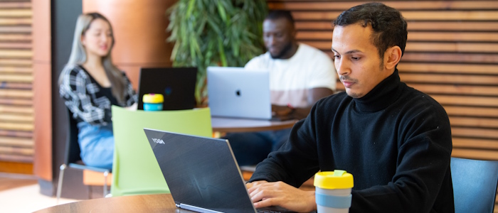 a student sitting using a laptop in the library