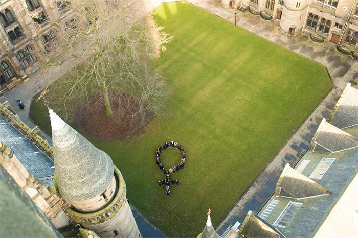 Students and staff make the female sign in the east quad