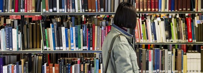 picture of a girl in looking at books in library 