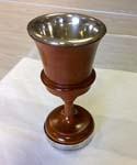 a wooden cup with a silver interior stands on a protective flat surface