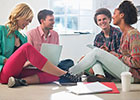 Four students sitting chatting in circle on the floor