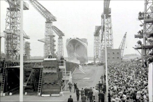 The QE2 is cheered by the crowds.
