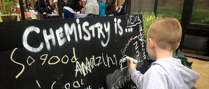 A boy writing on the chemistry thought board.