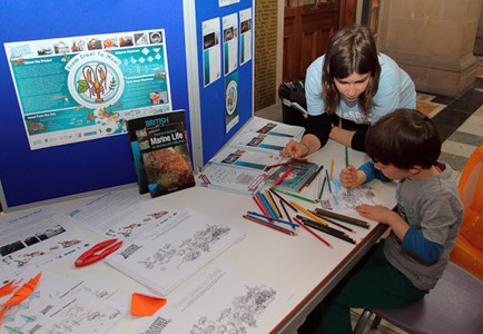 Photograph showing a GSF volunteer with a child doing creel themed colouring.