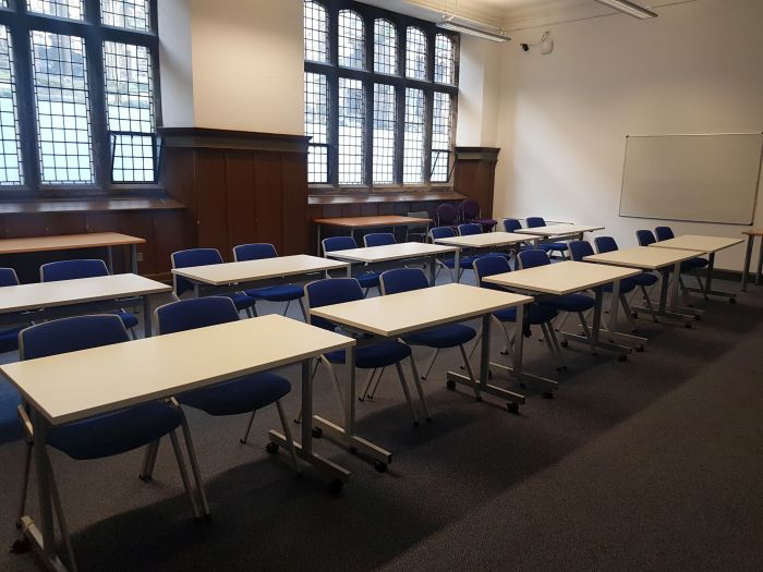 Flat floored teaching room with rows of tables and chairs.