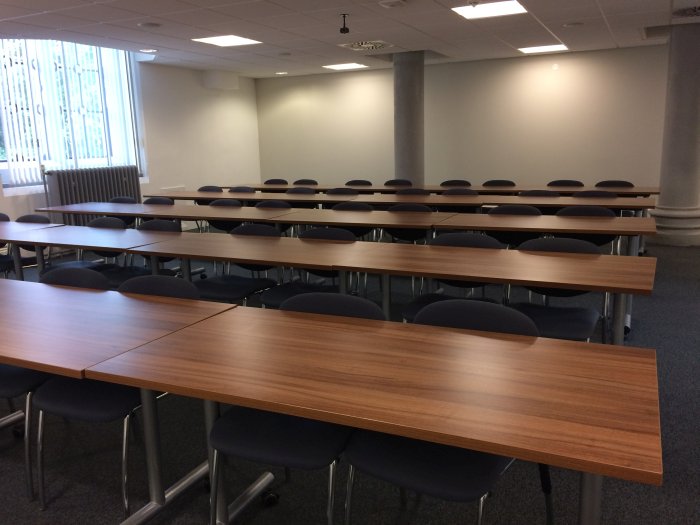 Flat floored teaching room with rows of tables and chairs